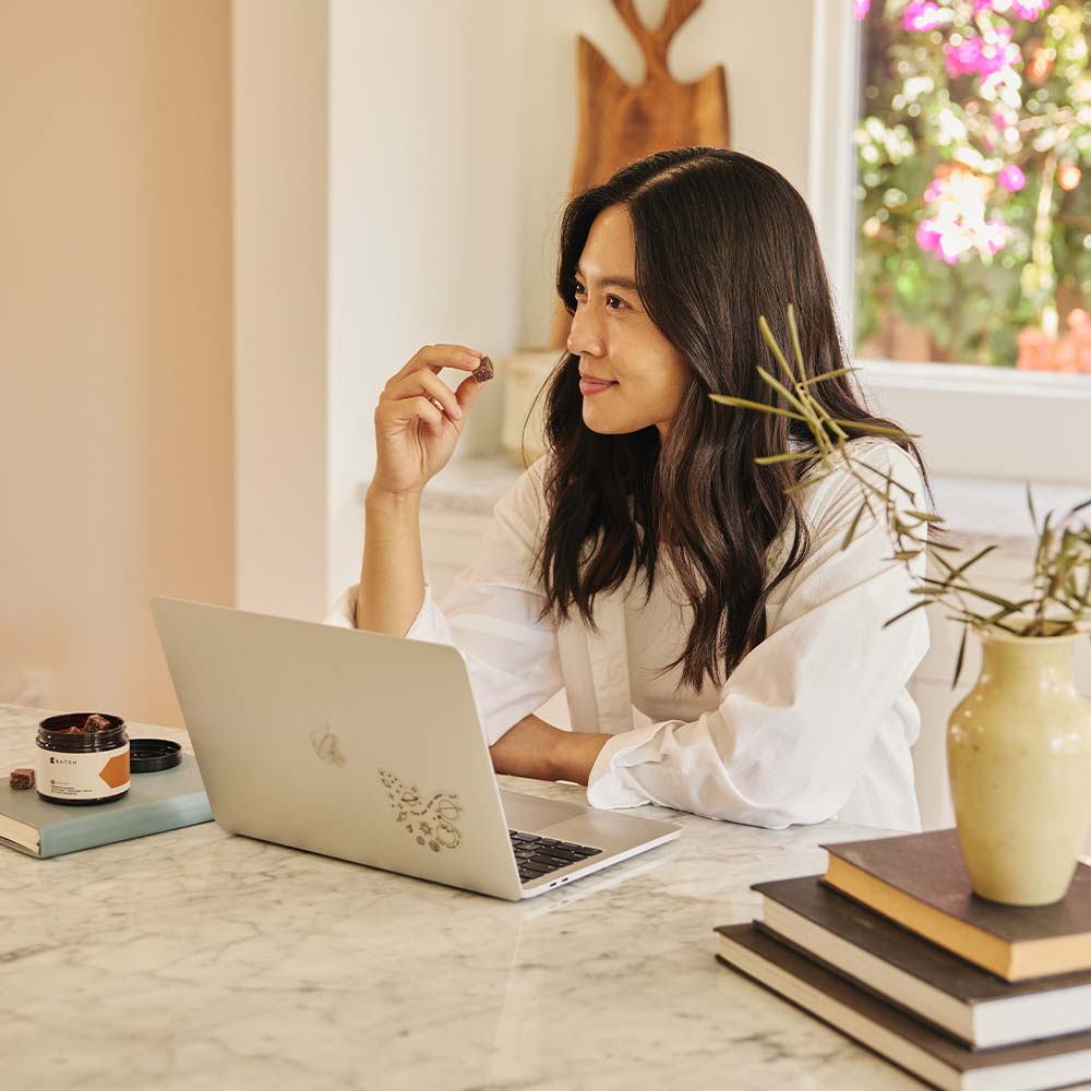 girl taking a brain boost gummy while working at a laptop