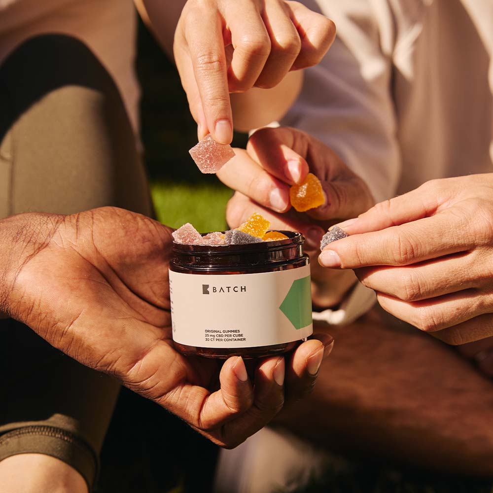 group of people reaching into CBD Gummies container taking a gummy each.